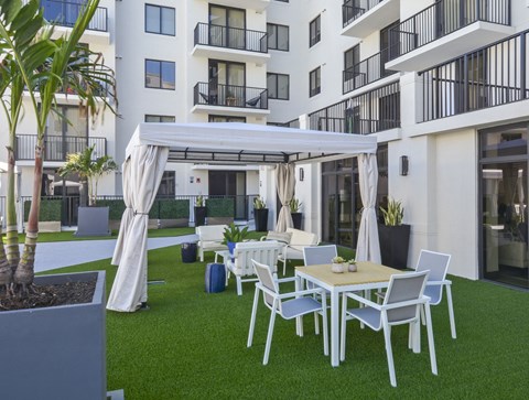 A white patio with a table and chairs under a white canopy.