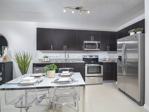 A modern kitchen with a dining table set for two.