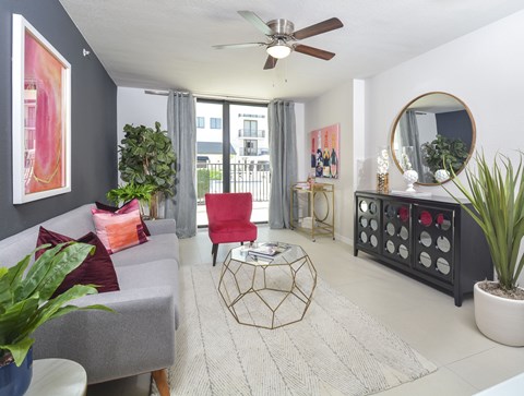 A living room with a grey couch, a red chair, a plant, and a mirror.