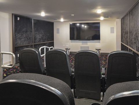 A row of black chairs are arranged in front of a screen.