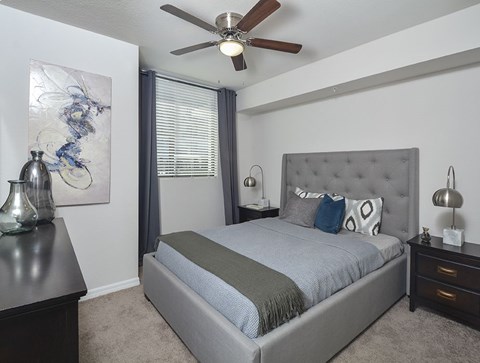 A bedroom with a bed, nightstands, and a ceiling fan.