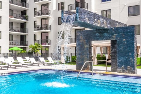 A pool with a waterfall feature in front of a building.