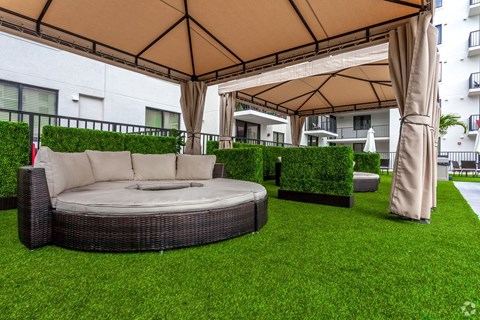 A patio with a round wicker sofa under a canopy.