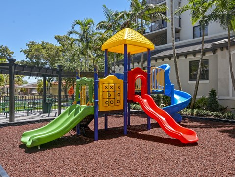 A playground with a yellow umbrella and a slide that says "cool" on it.
