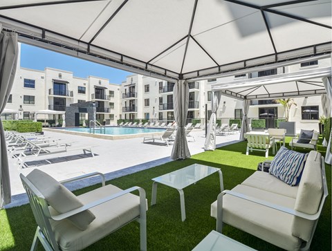 A white patio with chairs and a table is set up under a white canopy.