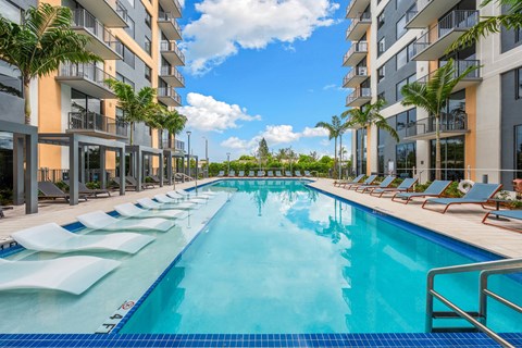 A long rectangular swimming pool with lounge chairs on the side.