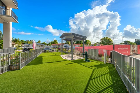 A grassy area with a small shelter and a fence with "NOW LEASING" written on it.