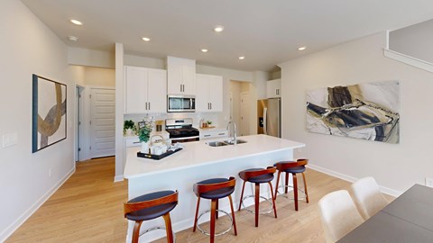 A kitchen with a white counter and bar stools.