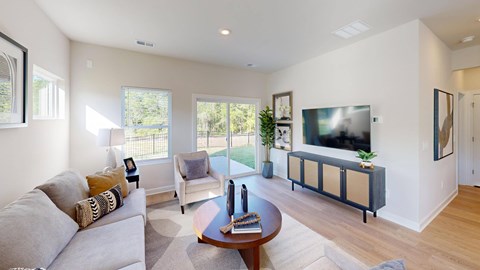 A living room with a grey couch, a brown coffee table, and a flat screen TV mounted on the wall.