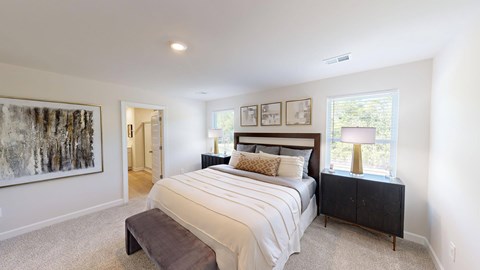 A bedroom with a large bed, a brown bench, and a painting on the wall.