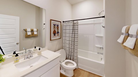 A white bathroom with a toilet, sink, and shower.