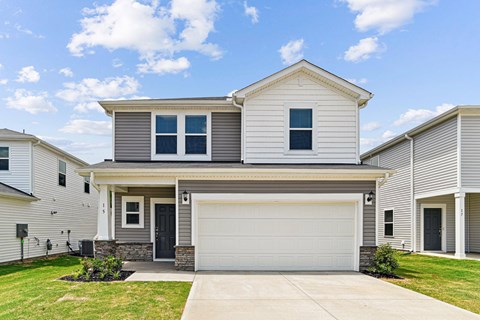 A two-story house with a garage door and a driveway.