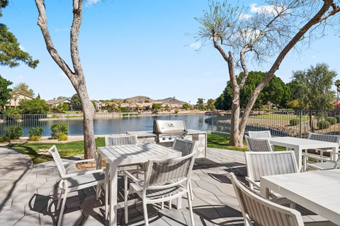 A patio with a table and chairs overlooking a lake.