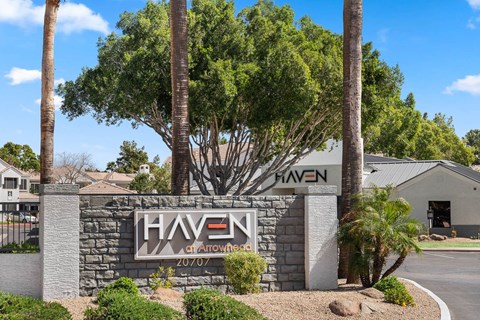 A sign for Haven at Arrowhead with a tree in front.