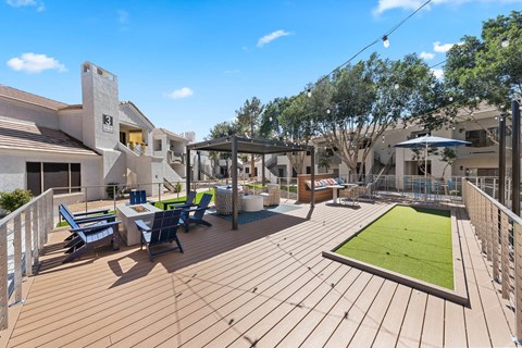 A wooden deck with a green lawn and blue chairs.