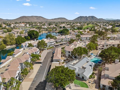 A bird's eye view of a residential area with houses, roads, and a lake.