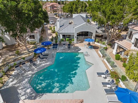 A swimming pool surrounded by a patio with chairs and umbrellas.