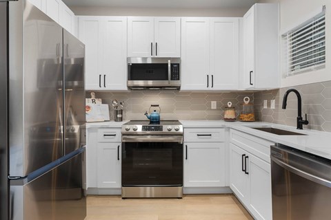 A modern kitchen with white cabinets and stainless steel appliances.