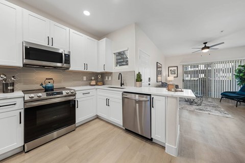 A modern kitchen with white cabinets and stainless steel appliances.