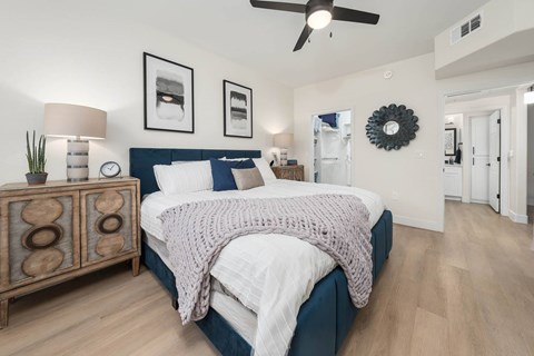 A bedroom with a bed, nightstand, and a ceiling fan.