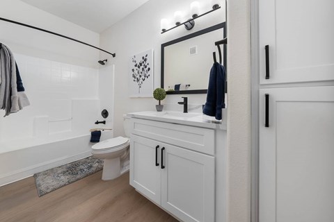 A white bathroom with a toilet, sink, and mirror.