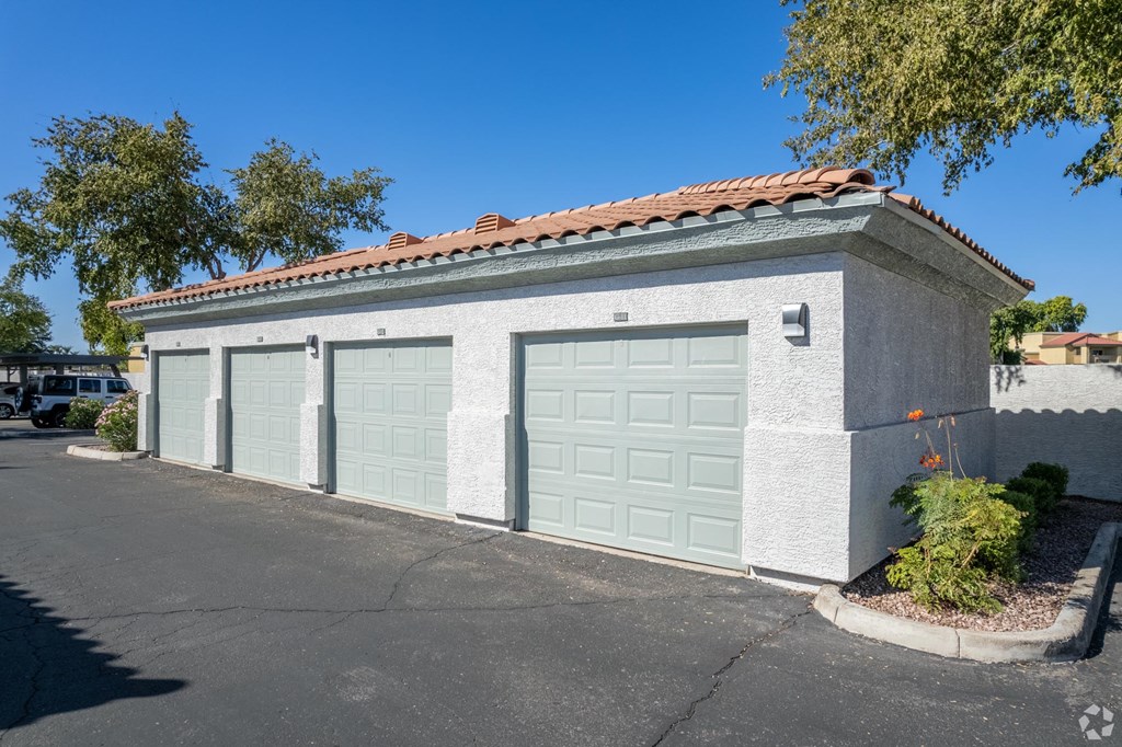 A two-car garage with a red tile roof and a small tree in front.