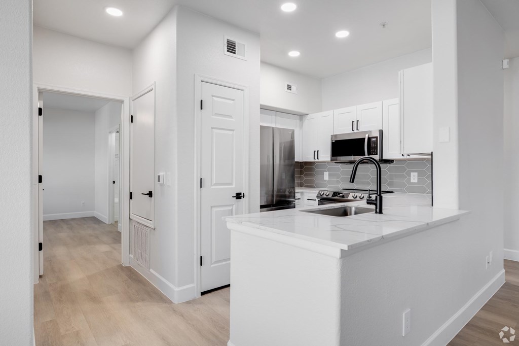 A white kitchen with a sink and a microwave.