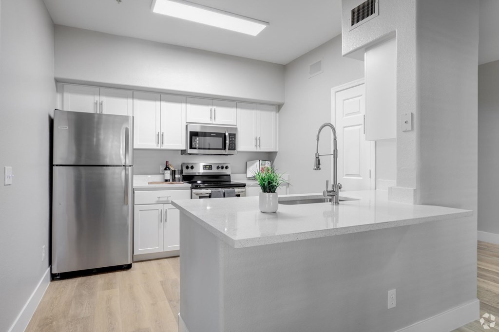 A modern kitchen with a stainless steel refrigerator and a white island.