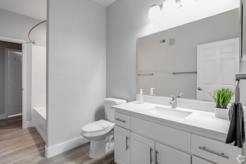 A white bathroom with a toilet, sink, and mirror.