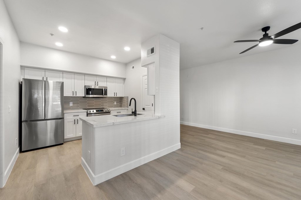 A modern kitchen with a stainless steel refrigerator and a wooden floor.