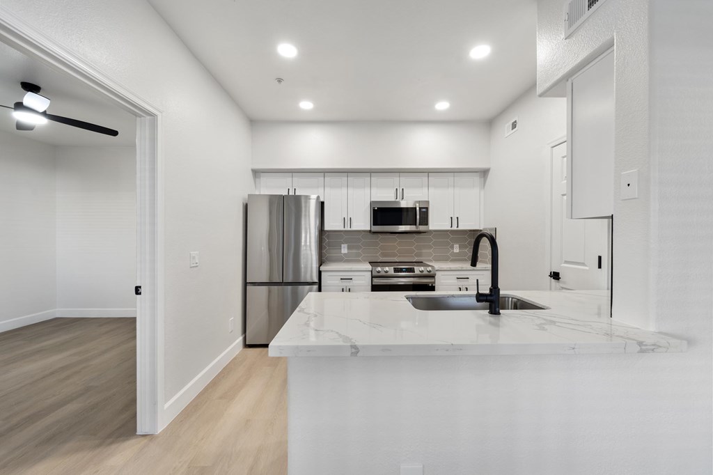 A modern kitchen with a white countertop and stainless steel appliances.