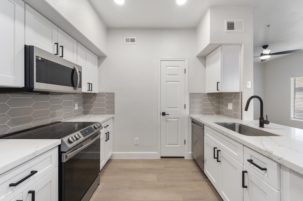 A modern kitchen with white cabinets and a black countertop.