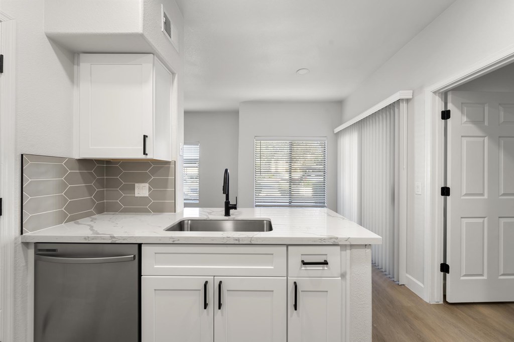 A modern kitchen with white cabinets and a marble countertop.