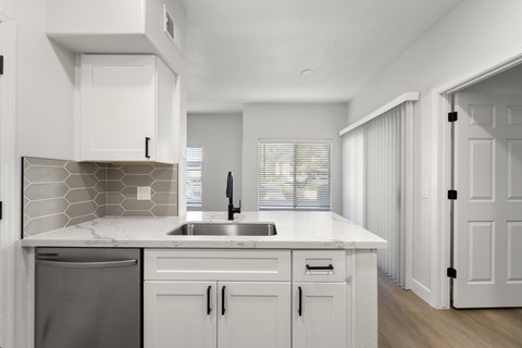 A modern kitchen with white cabinets and a marble countertop.