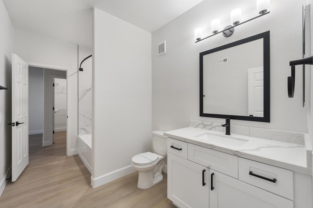 A bathroom with a toilet, sink, and mirror.