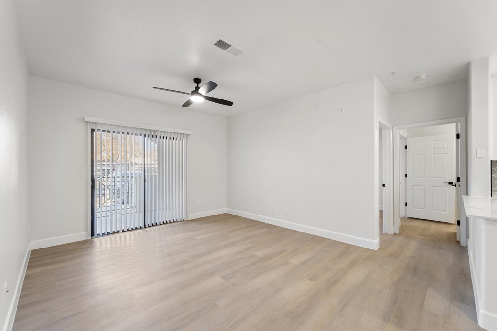 A room with a ceiling fan and sliding glass doors.