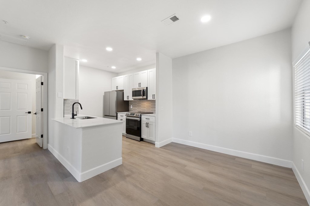 A kitchen with white cabinets and a white island with a sink.