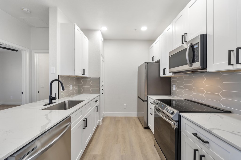 A modern kitchen with white cabinets and stainless steel appliances.