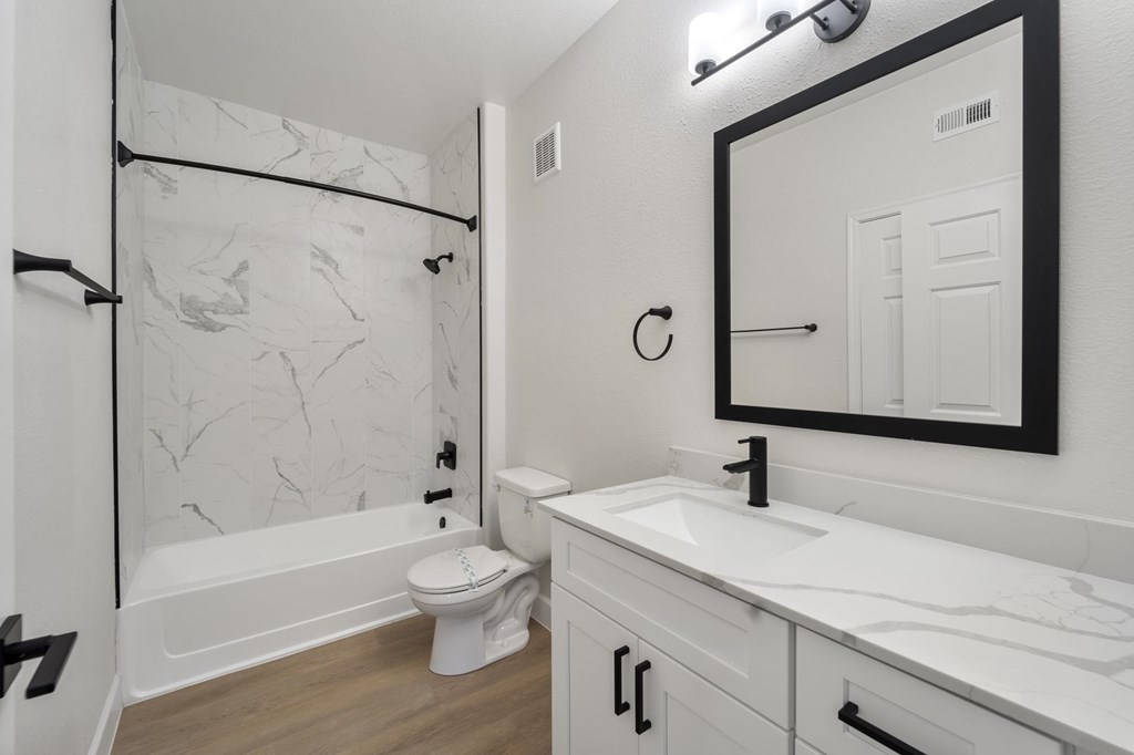 A white bathroom with a marble patterned shower.