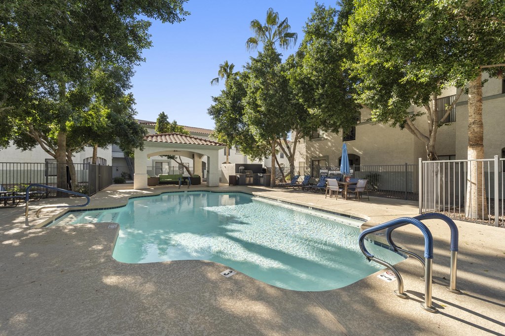 A pool surrounded by trees and a building in the background.