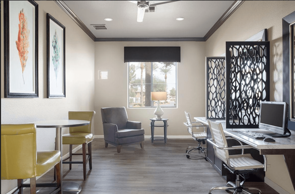 A room with a desk, chairs, and a computer.