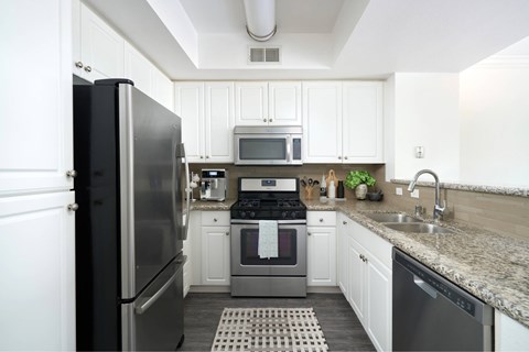 A kitchen with a black refrigerator and white cabinets.