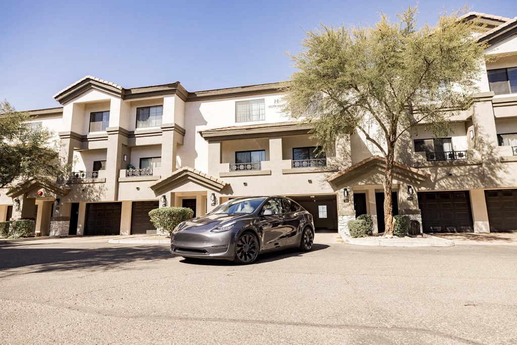A silver car is parked in front of a multi-story apartment building.