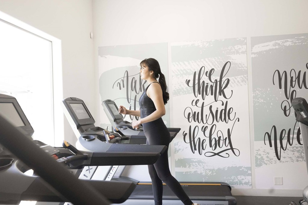 A woman is running on a treadmill in a gym.