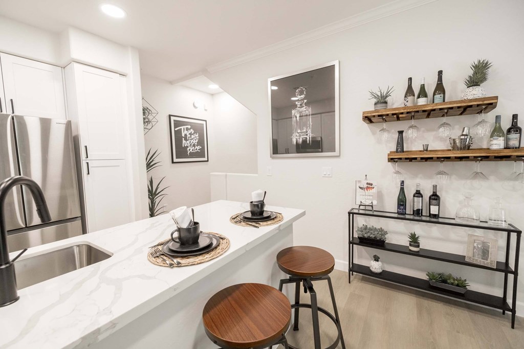 A kitchen with a white marble countertop and a wooden stool.