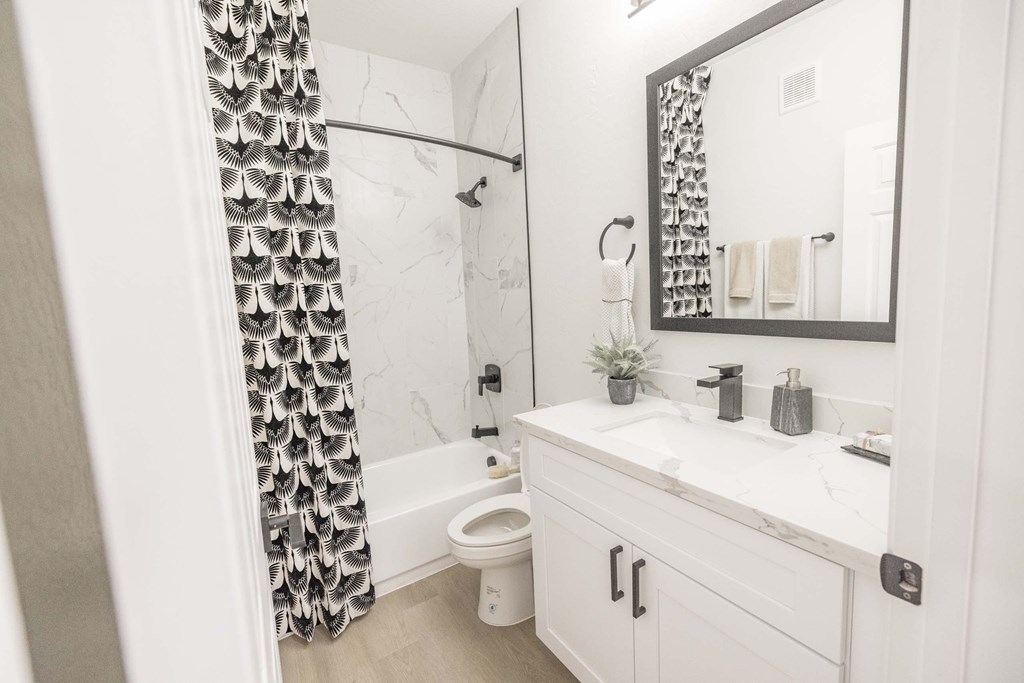 A white bathroom with a black and white shower curtain.