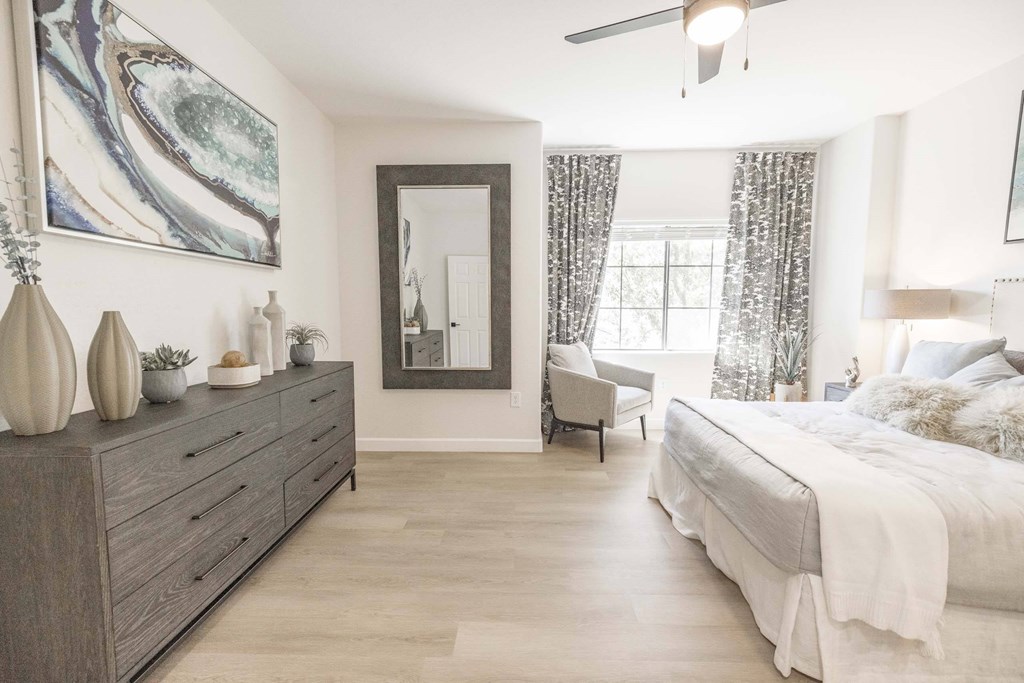 A bedroom with a large bed, a dresser, and a mirror.