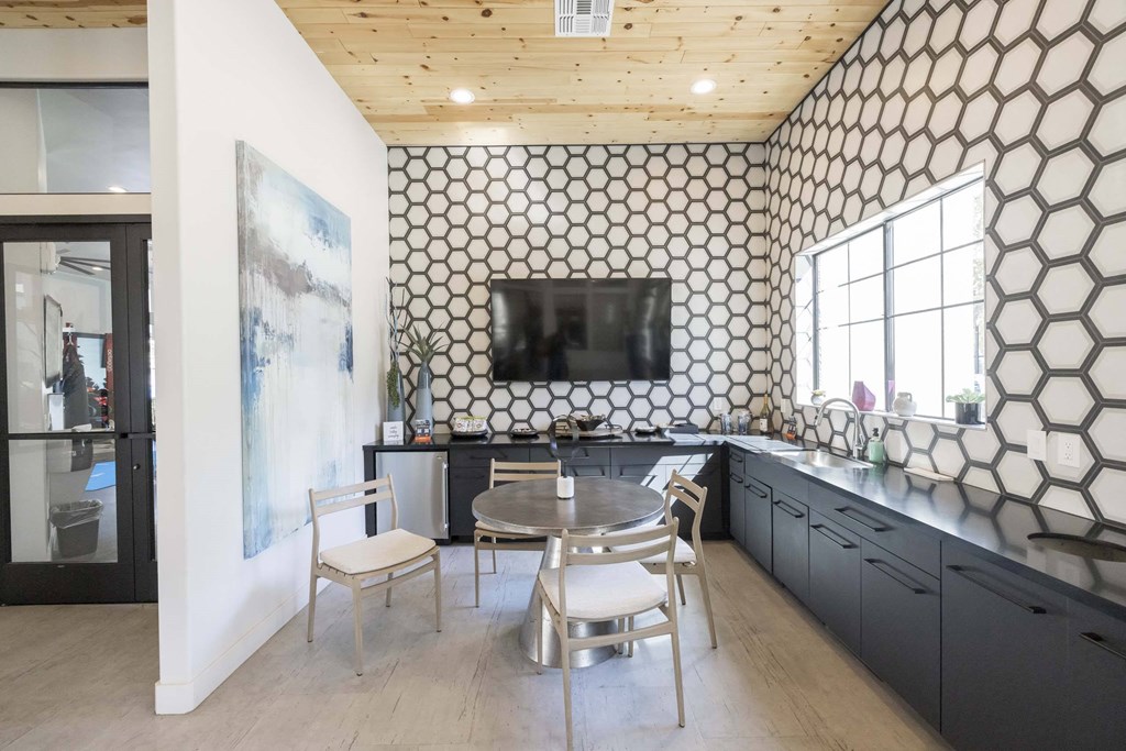 A kitchen with a black and white patterned backsplash and wooden ceiling.