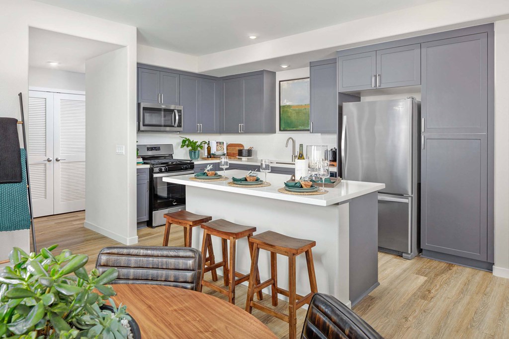 A kitchen with a white countertop and grey cabinets.
