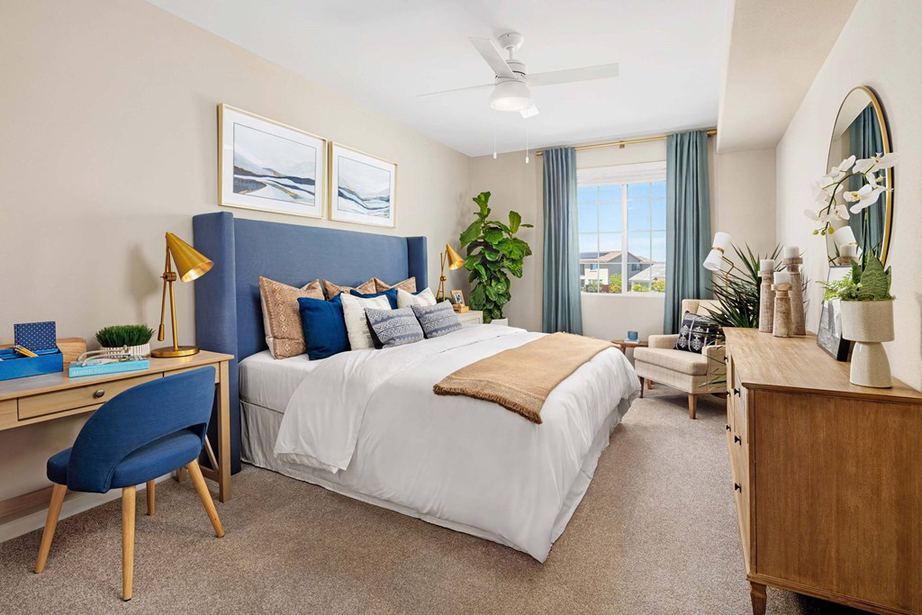 A bedroom with a large bed, a desk with a chair, and a dresser with a mirror.